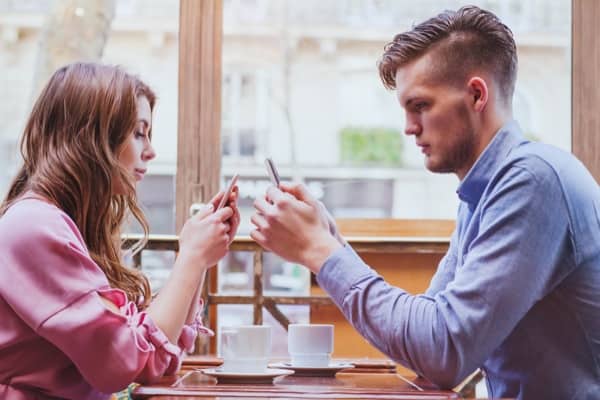 Dating couple with smartphones. Consulting Artificial Intelligence
