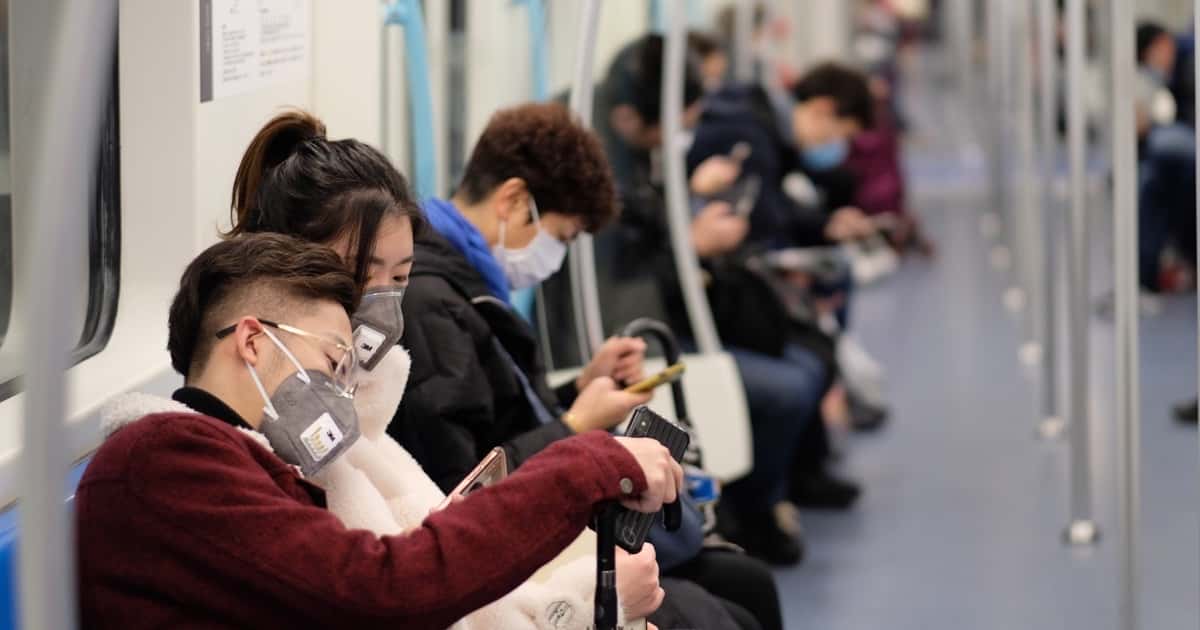 People wearing masks and using their smartphones.