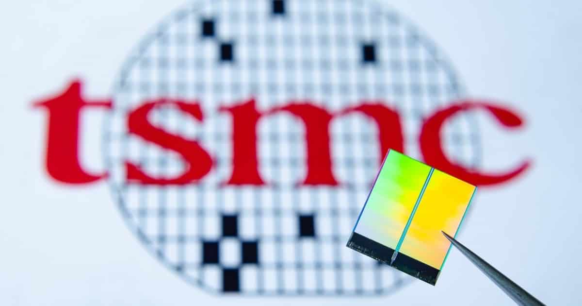 Photo of a silicon chip in front of the TSMC logo.