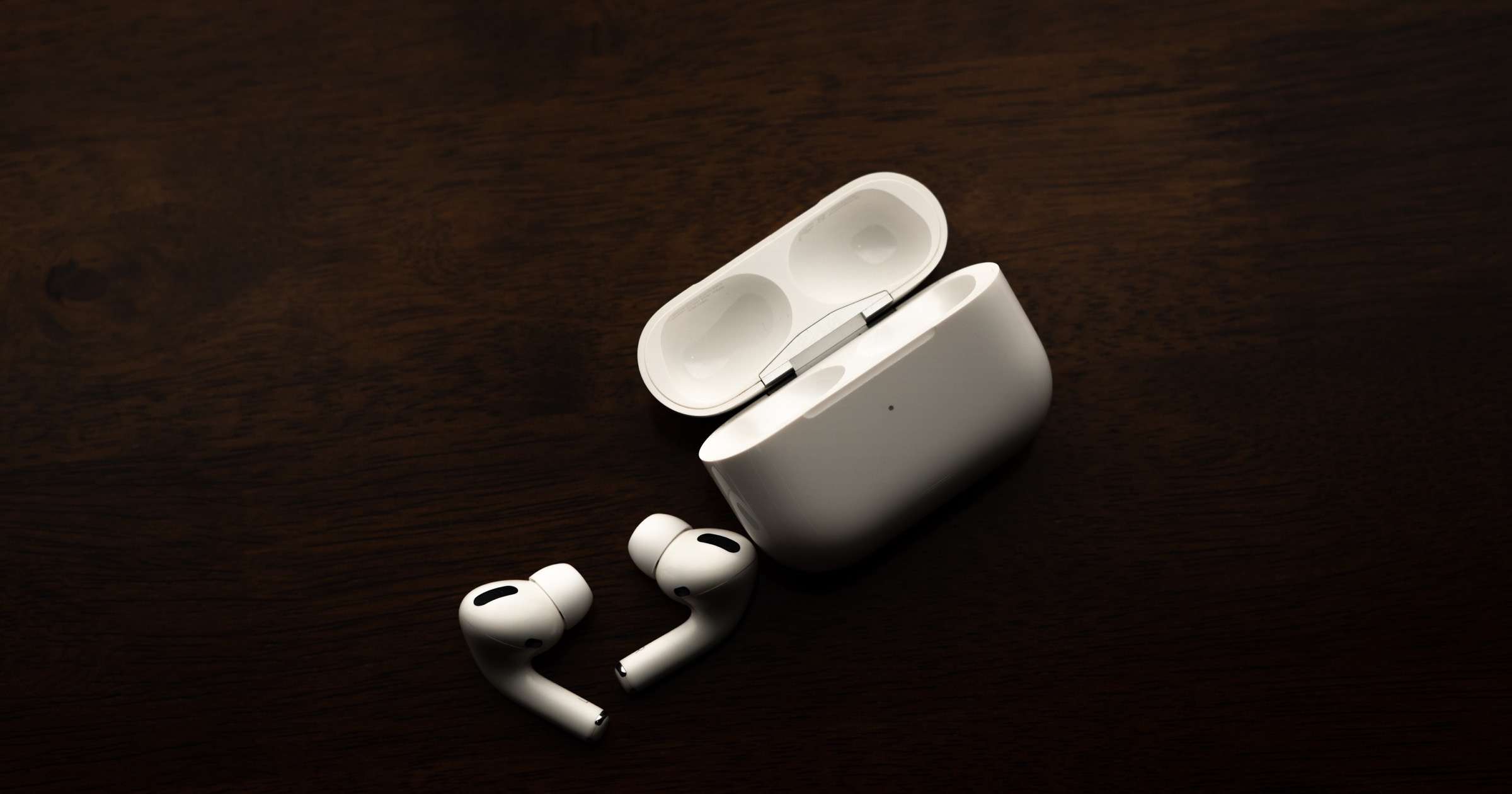 AirPods Pro against a dark brown background.