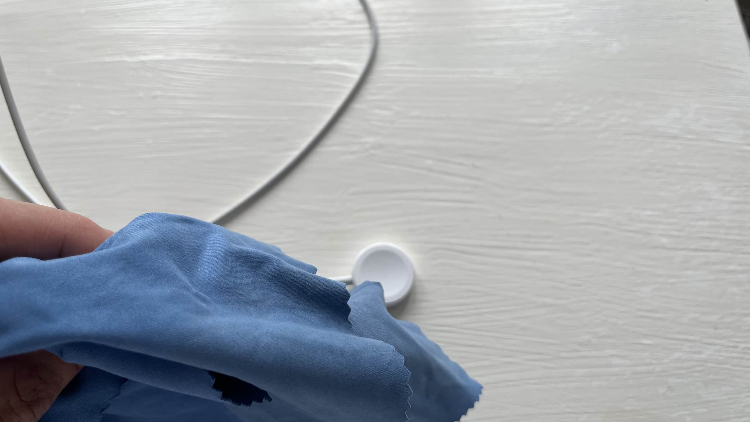 Photo of an Apple Watch charger and a blue microfiber cloth