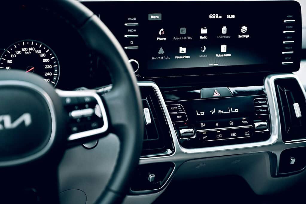 Close-up of a car's dashboard featuring a digital display, speedometer, and climate controls, highlighting modern technology and design.