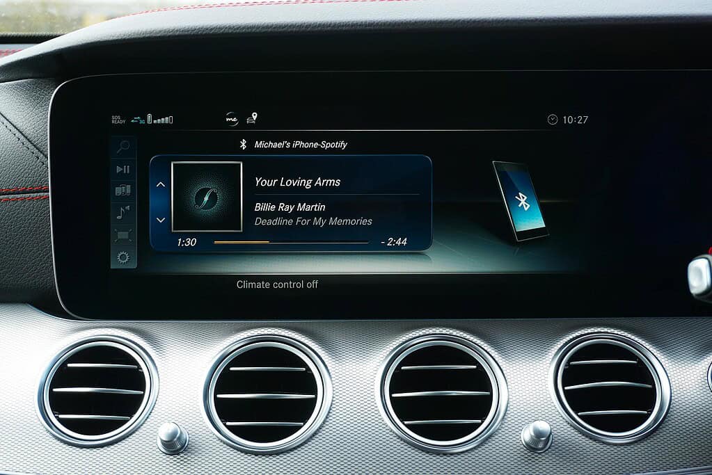 Car dashboard display showing Spotify track "Your Loving Arms" by Billie Ray Martin, with song progress and Bluetooth connectivity icon.