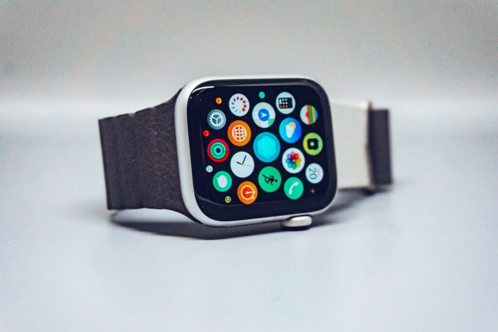 A sleek smartwatch with a square face and a textured brown strap, displaying colorful app icons on its screen.