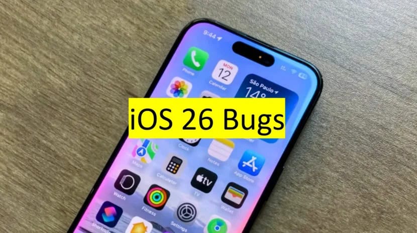 iPhone on wooden surface showing home screen with yellow banner overlay reading “iOS 26 Bugs,” highlighting known issues in the update.