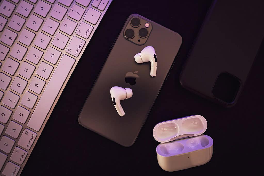 Apple AirPods resting next to a sleek Apple keyboard on a clean surface, showcasing modern tech accessories.